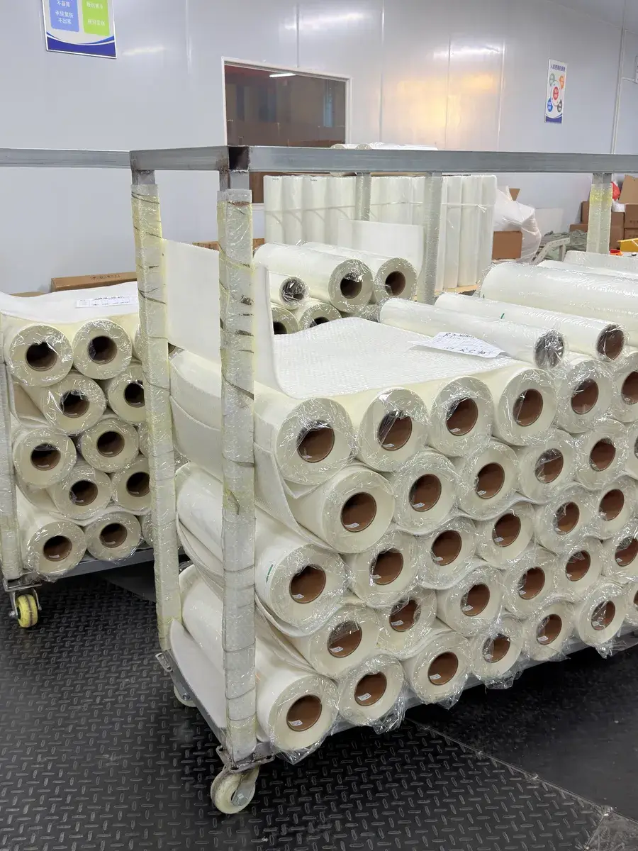Finished DTF film rolls wrapped on paper cores and stacked on trolleys