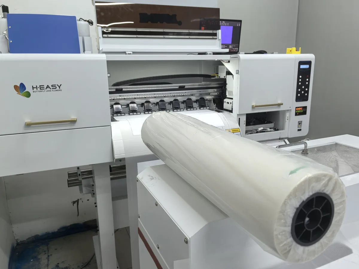 A roll of DTF transfer film loaded on a 60 cm DTF printer