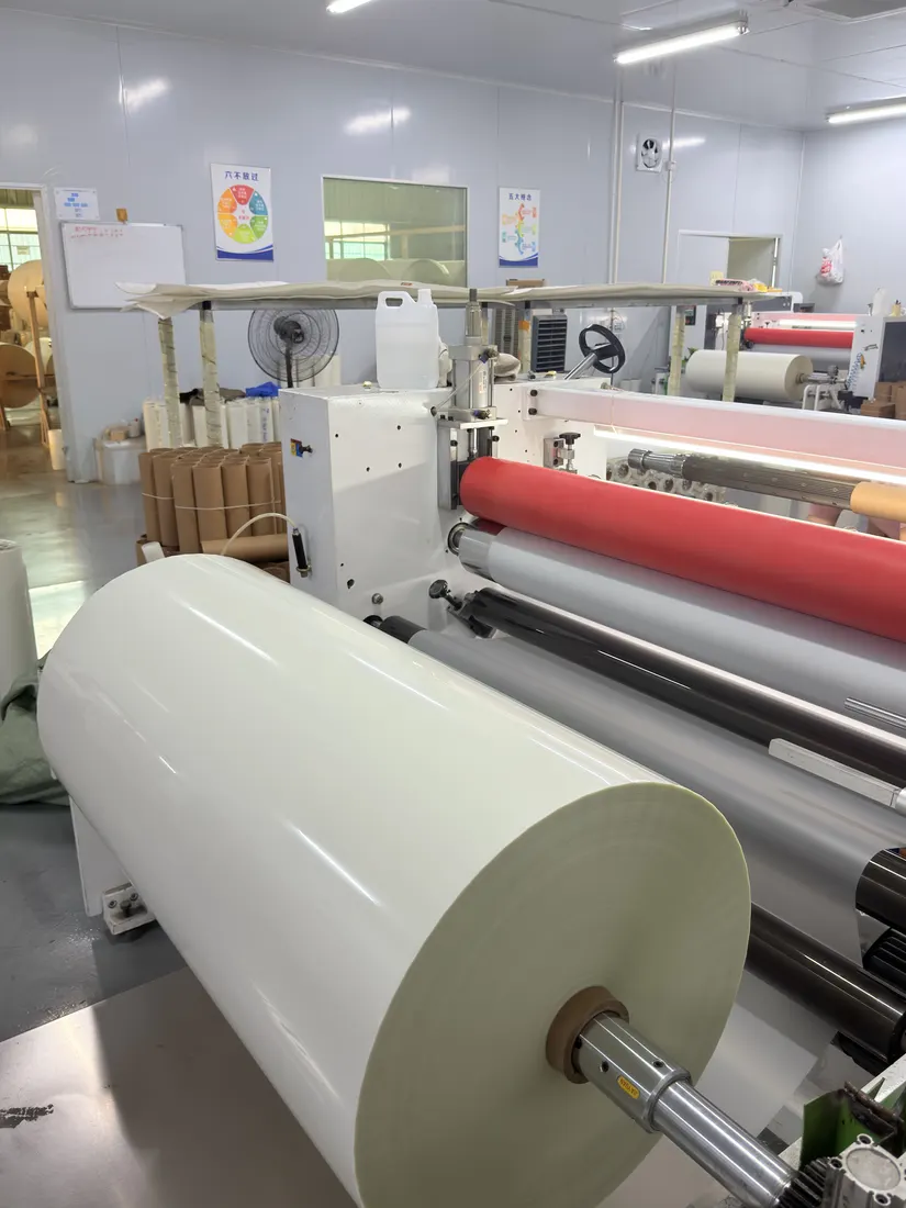 A large master roll of white film mounted on a rewinding machine