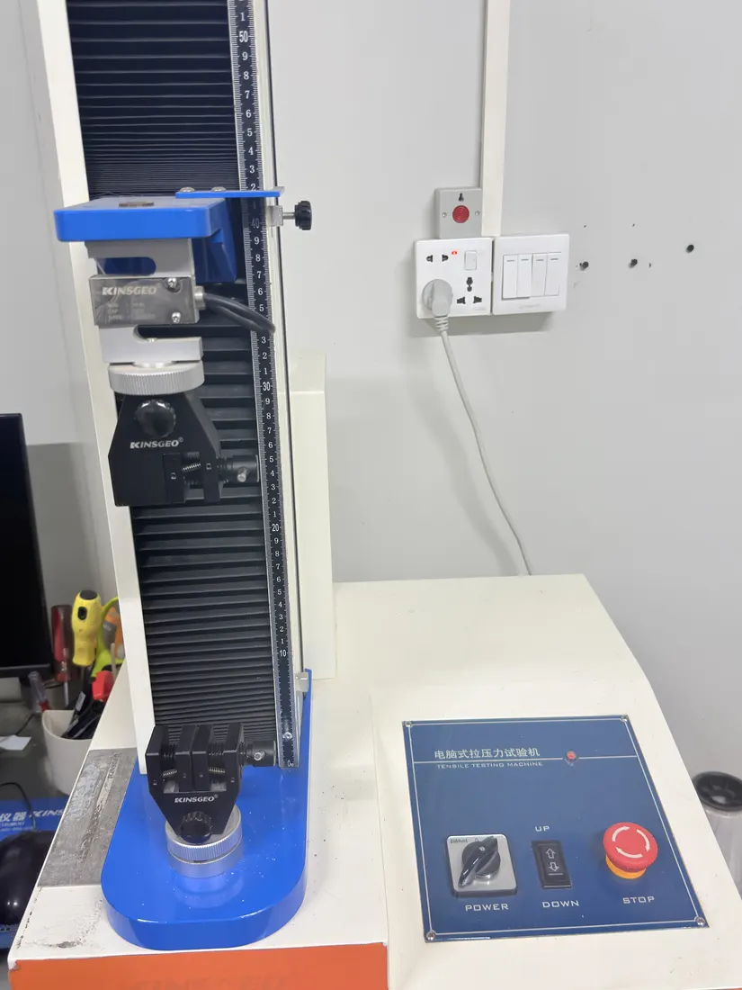 A material testing machine with a control panel on a bench in the plant