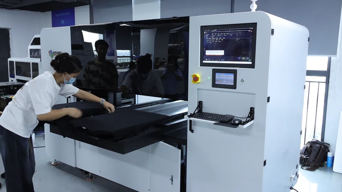 Operator smoothing a dark garment onto one HY 2D DTG platen