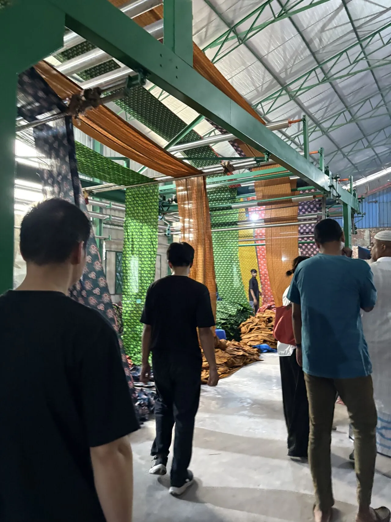 Visitors walking beneath hanging fabric in a textile factory
