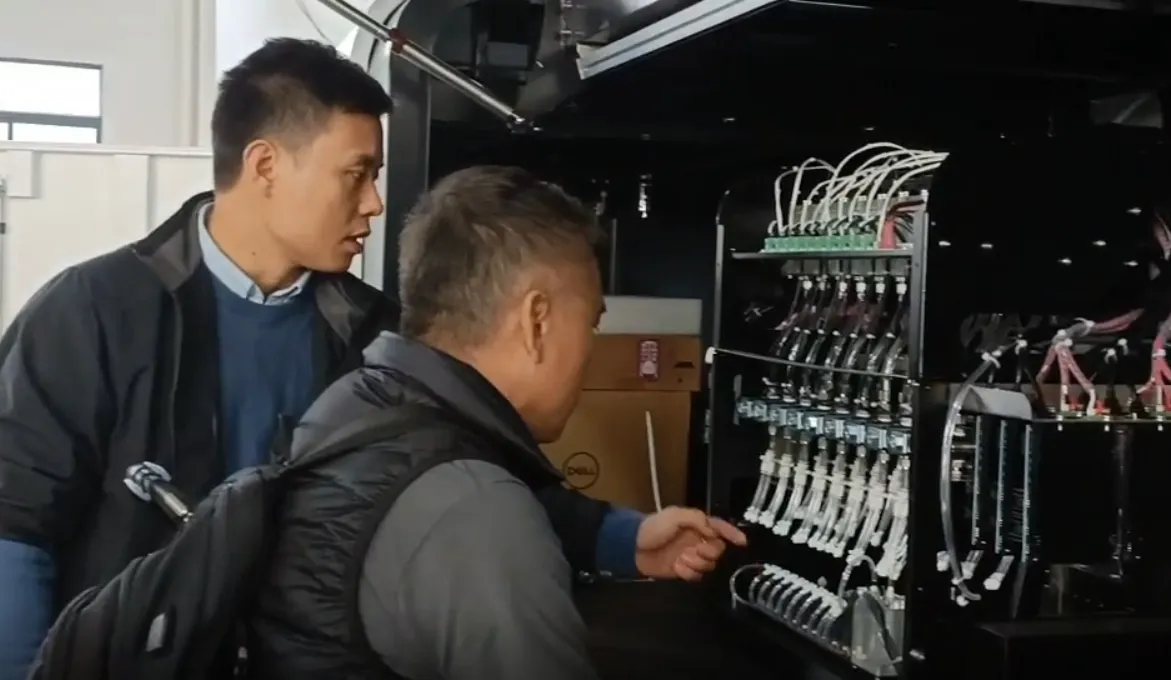 Visitors examining the printhead assembly of a textile printer during the factory visit