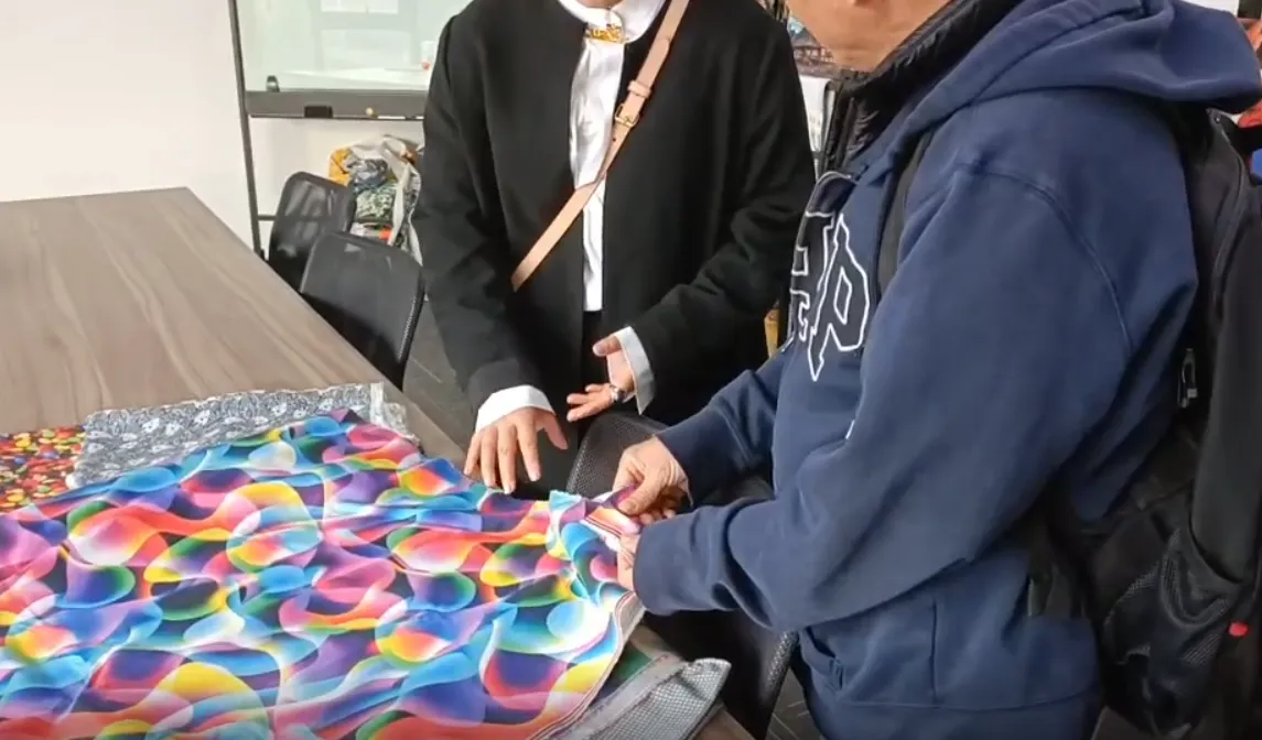 Factory visitors inspecting a colorful printed fabric sample