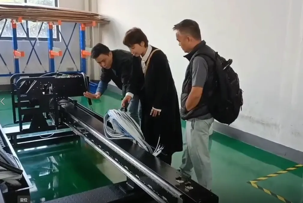 Factory visitors discussing textile printer components beside the machine