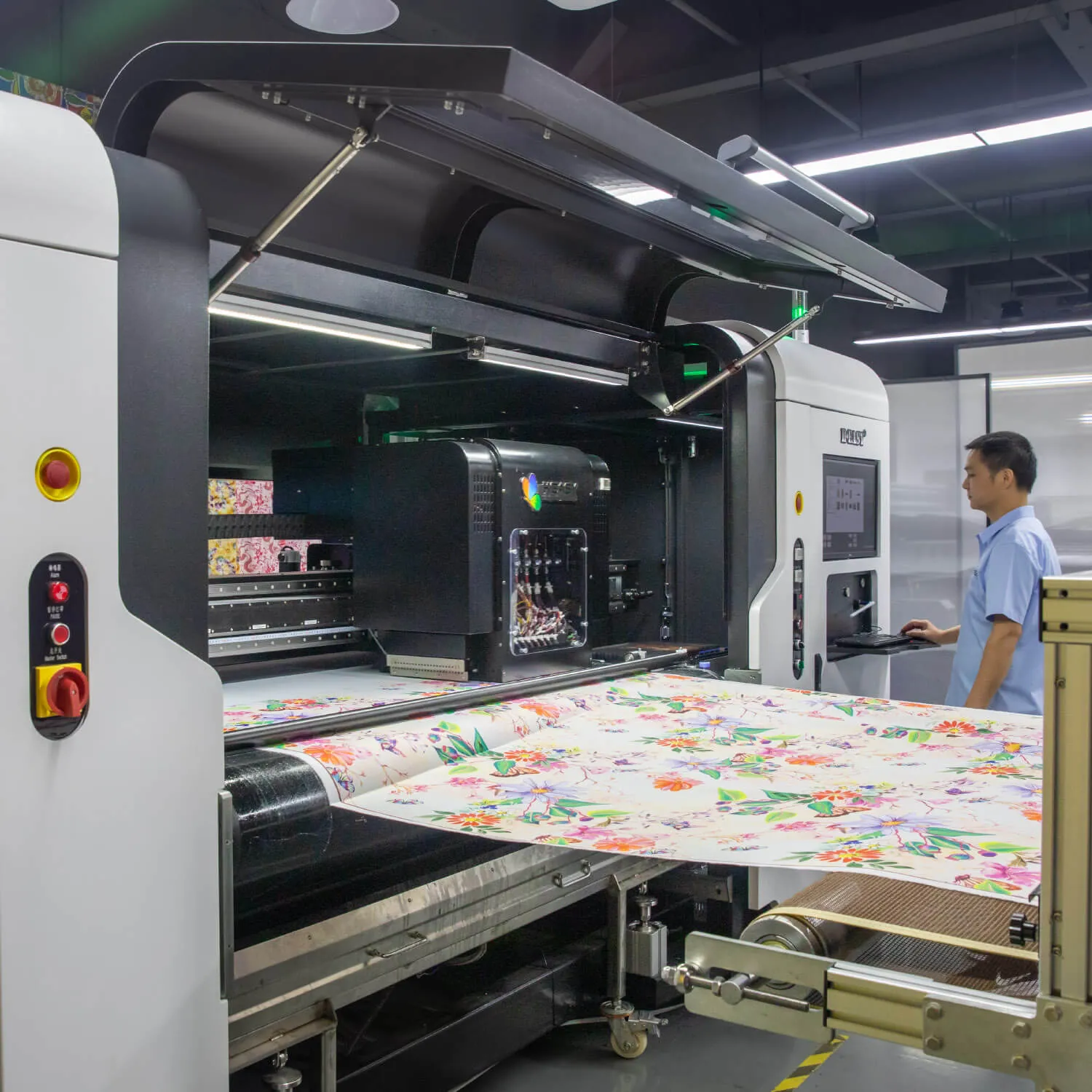 Roll-to-roll textile printer producing a floral fabric print with an operator alongside