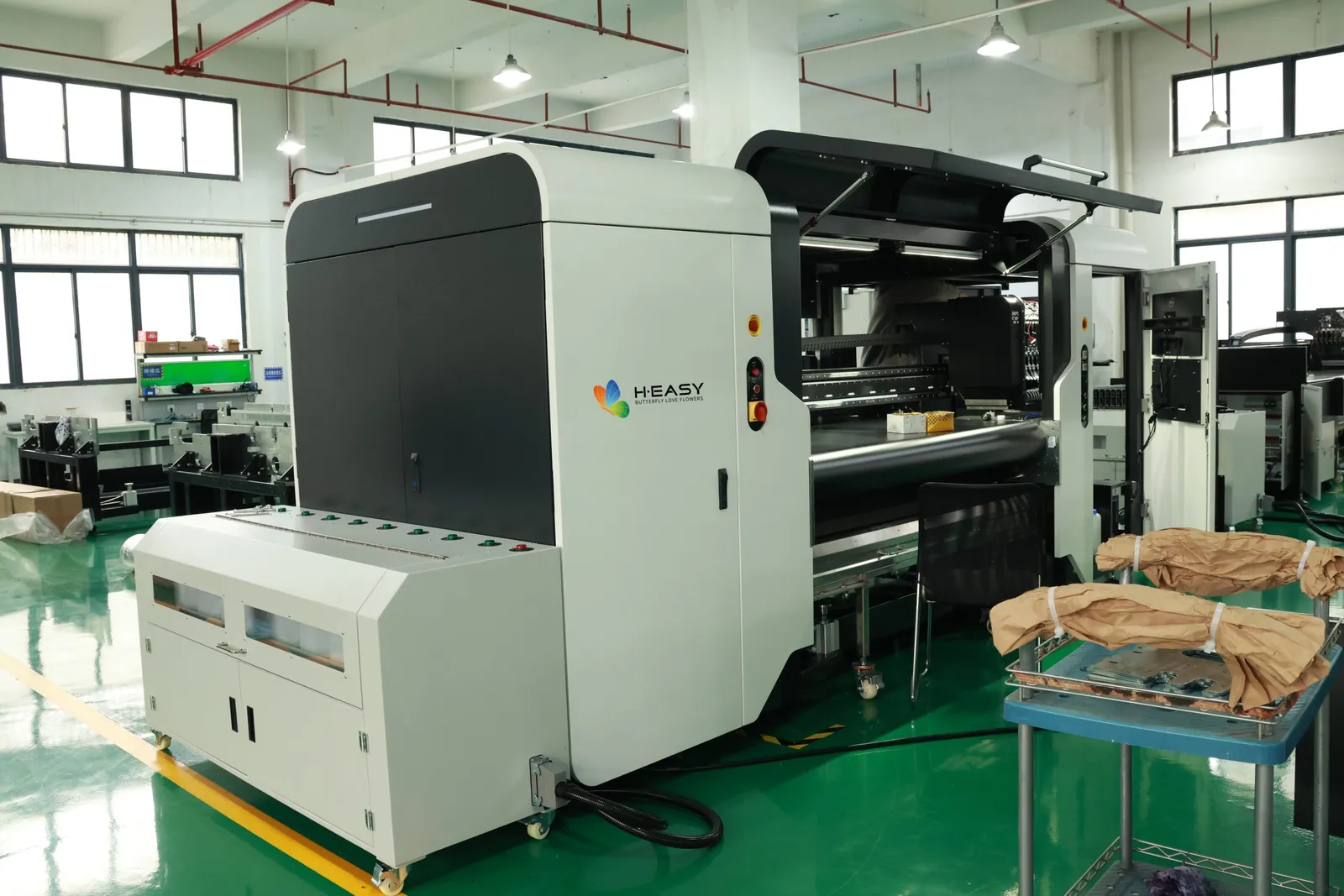 Impresora textil industrial de bobina a bobina con la bahía de impresión abierta en una nave de fábrica