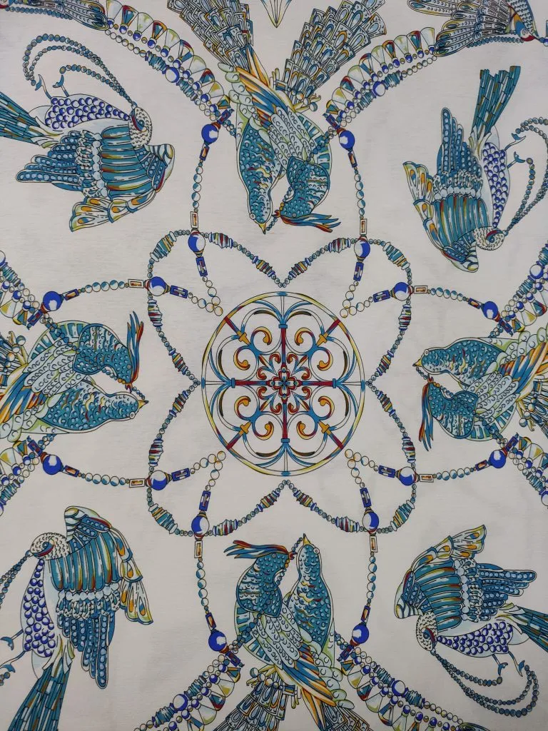 Vista cercana de motivos de pájaros azules y dorados con contornos finos impresos sobre tejido claro
