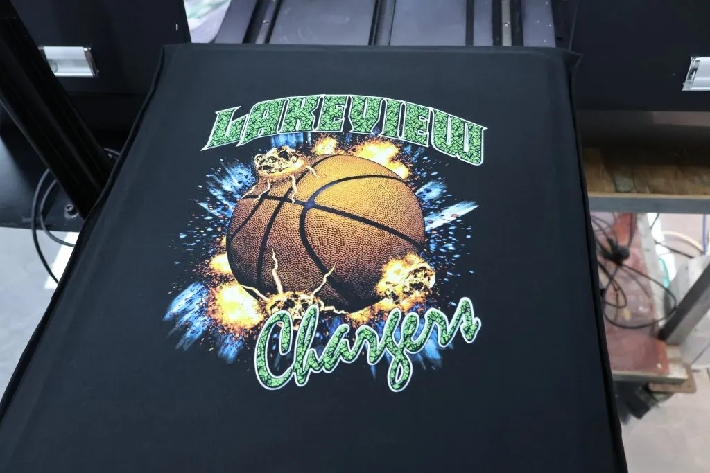 Camiseta preta numa mesa DTG com um gráfico de basquete estampado no peito