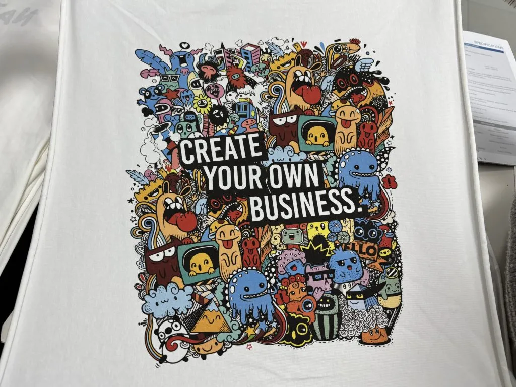 Vista aproximada de um gráfico de desenho multicolorido impresso numa camiseta branca esticada