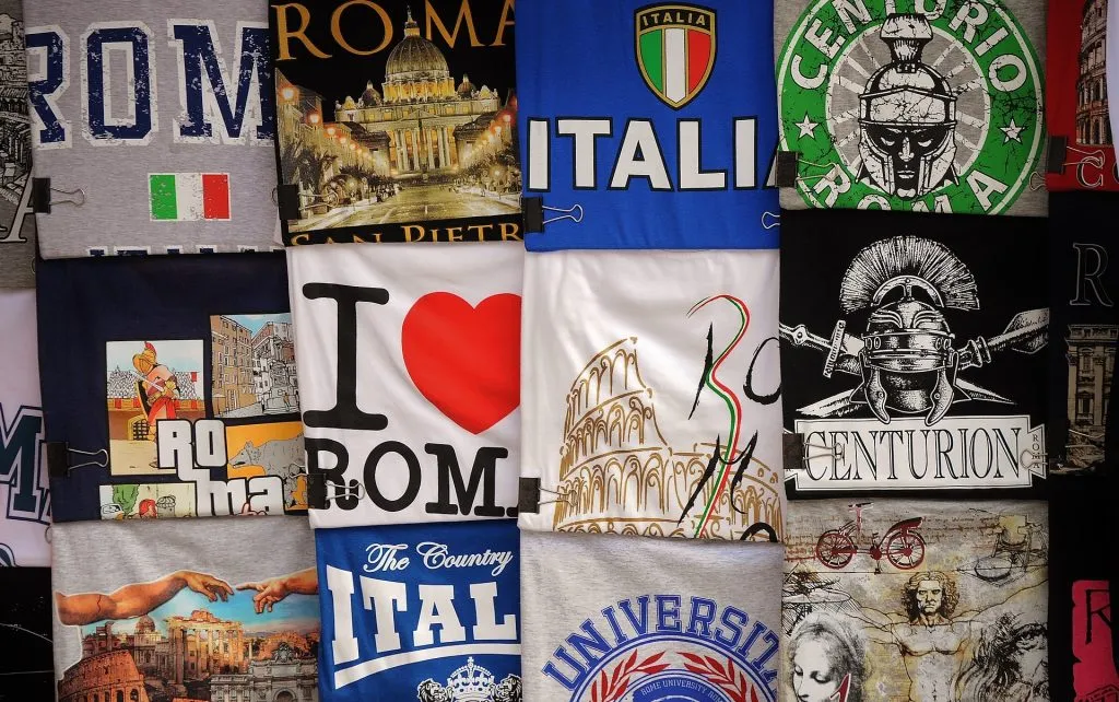 Expositor de camisetas estampadas dobradas com gráficos temáticos de Roma e da Itália