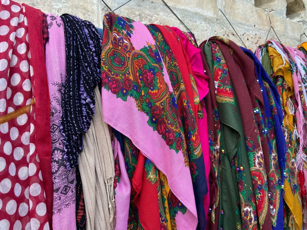Fileiras de tecidos e lenços de estampas vivas pendurados juntos em uma exposição ao ar livre