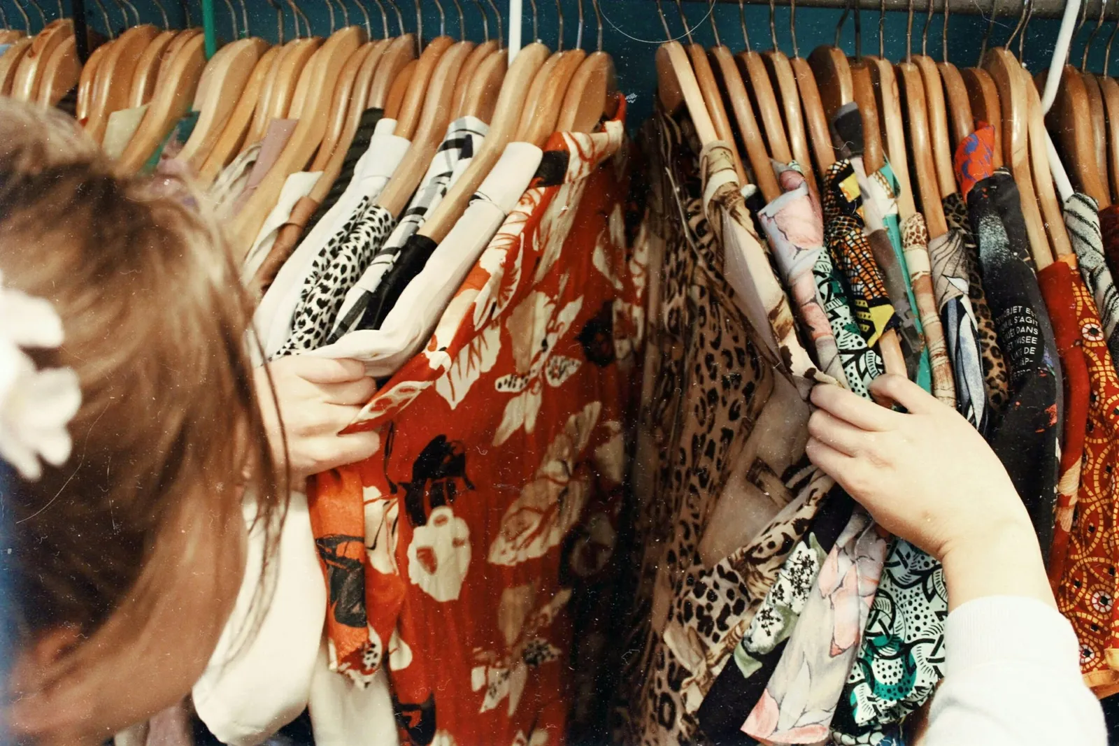 Clienta comparando prendas estampadas colgadas en barras de madera