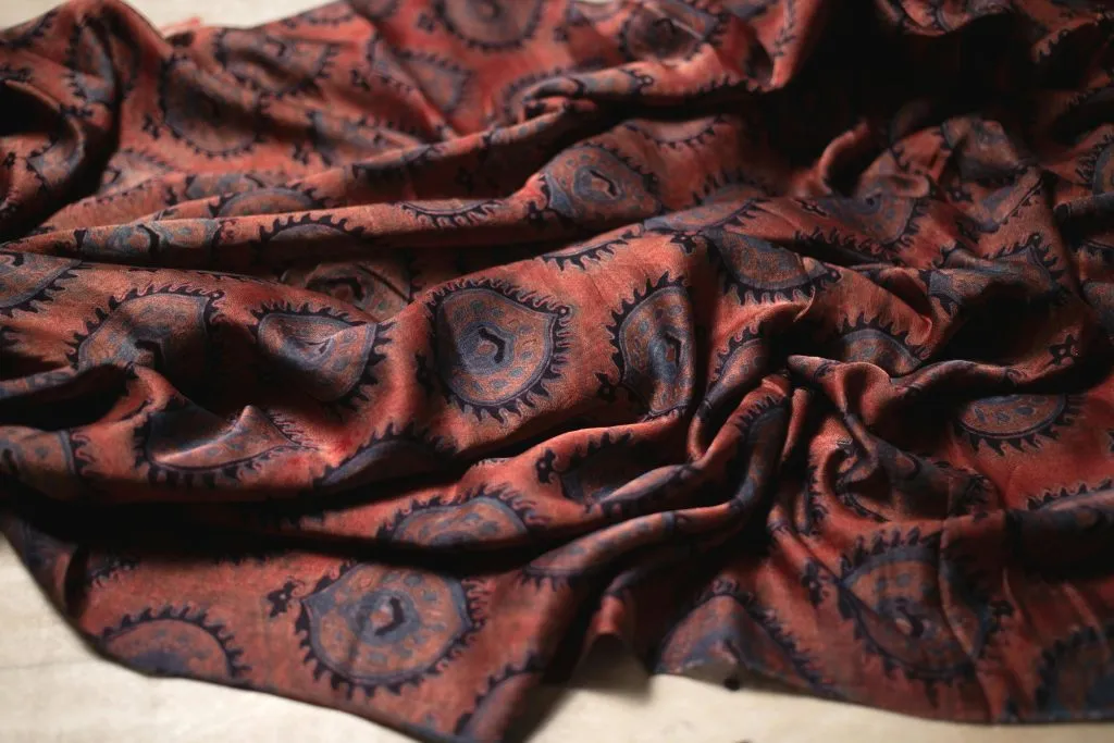 Tejido estampado color óxido plegado para mostrar motivos de cachemir repetidos y la textura de la superficie
