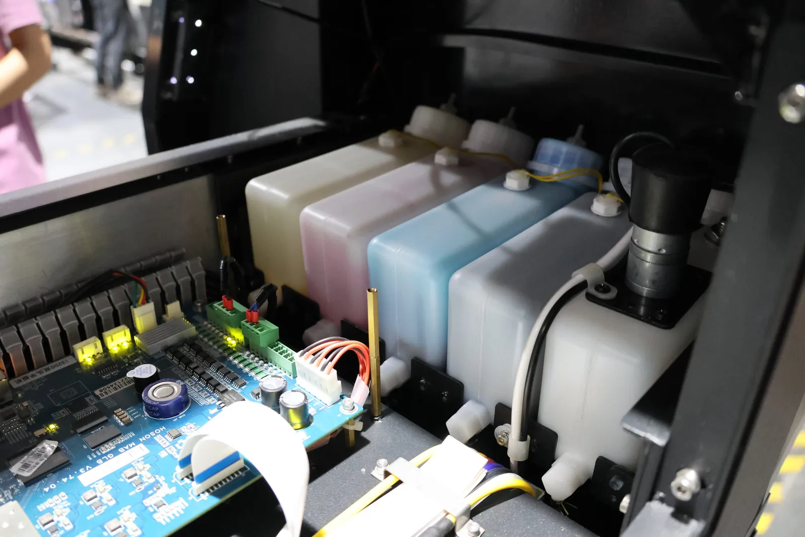 Bahía de servicio abierta de una impresora con depósitos de tinta translúcidos, tubos y una placa de control