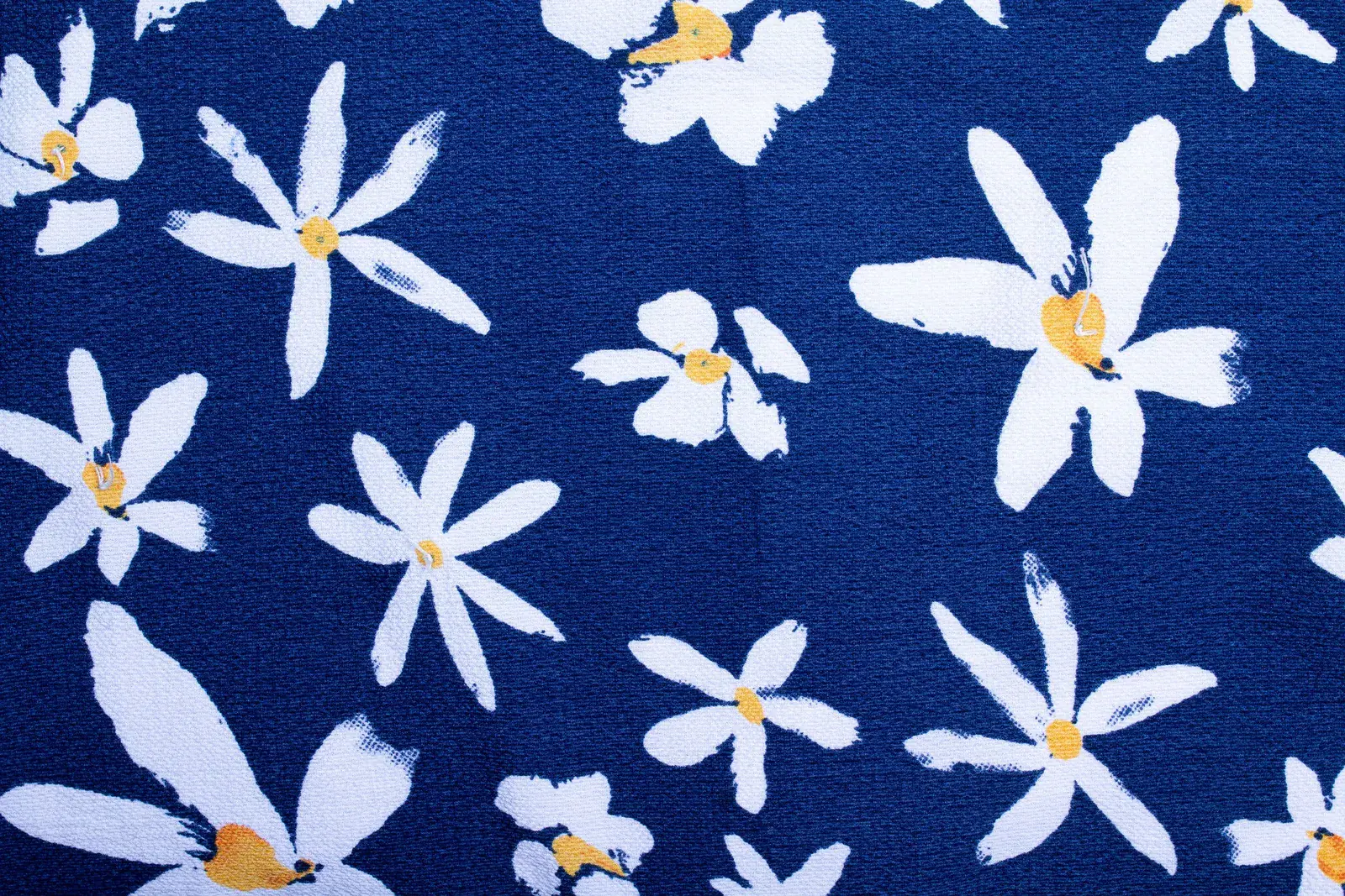 Vista cercana de motivos florales blancos y amarillos impresos sobre tejido azul texturizado