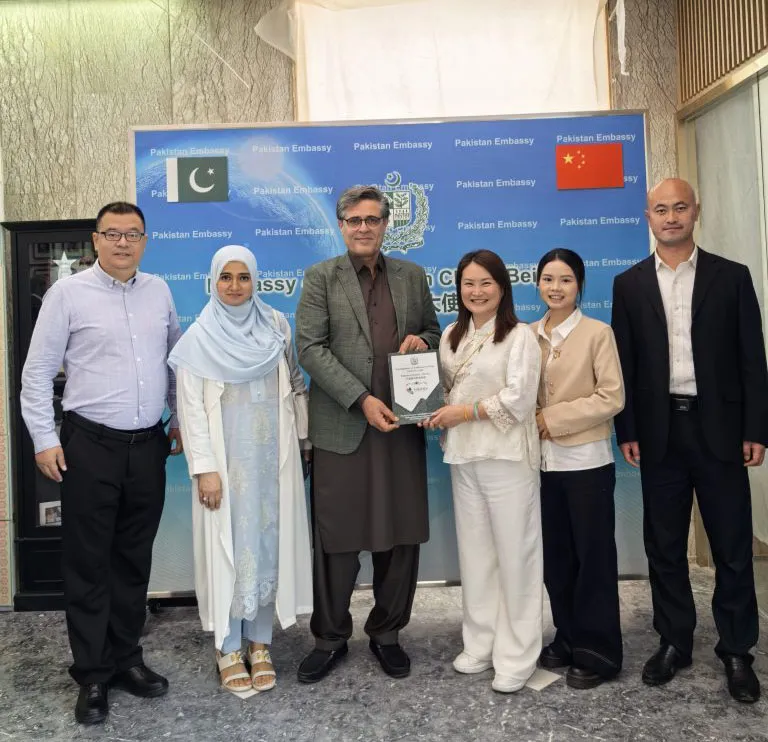 Representantes de la empresa e invitados de la Embajada de Pakistán sostienen una placa de reconocimiento benéfico en Pekín