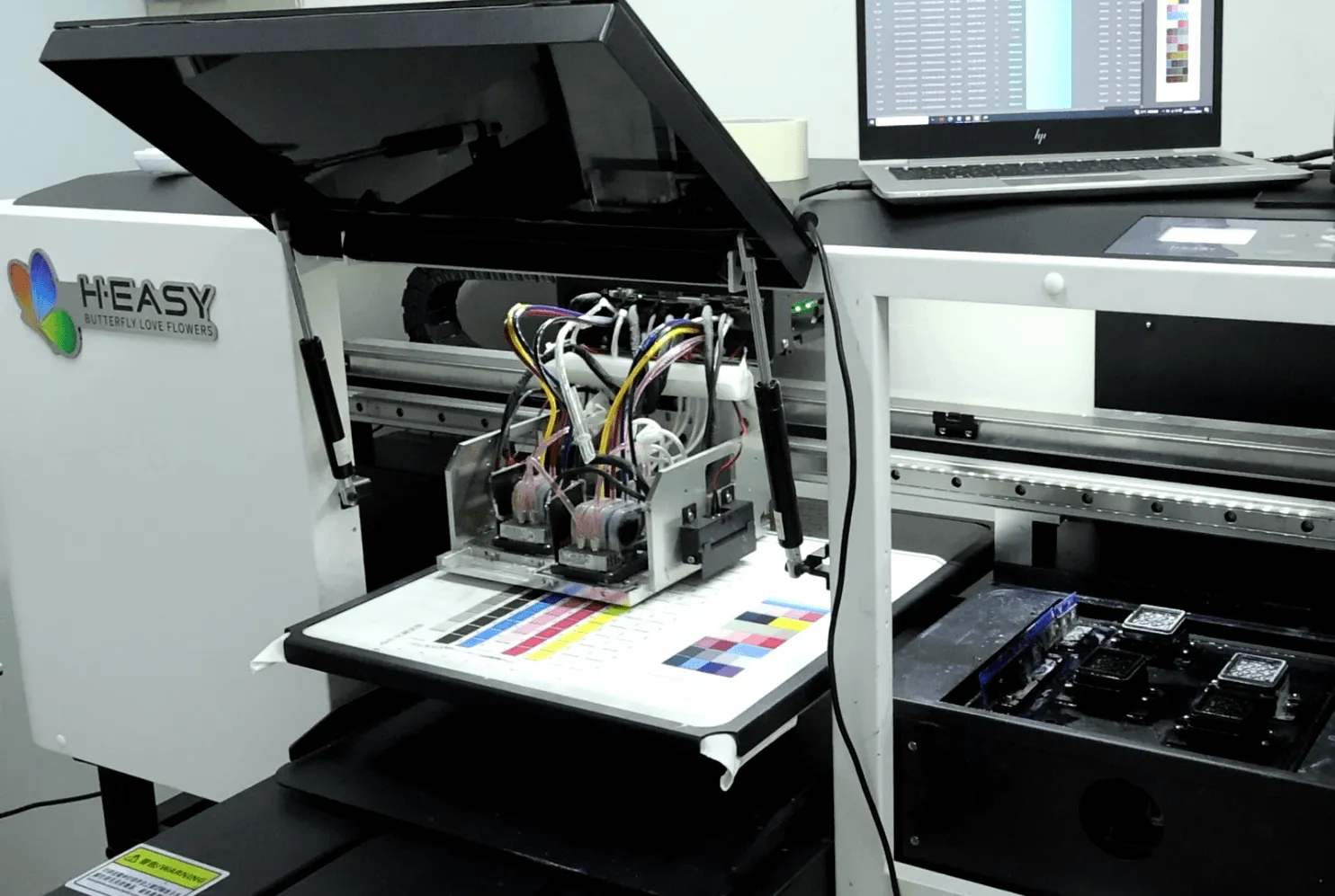 Impressora DTG HY-4050 com a mesa aberta durante a preparação da impressão ao vivo em uma peça
