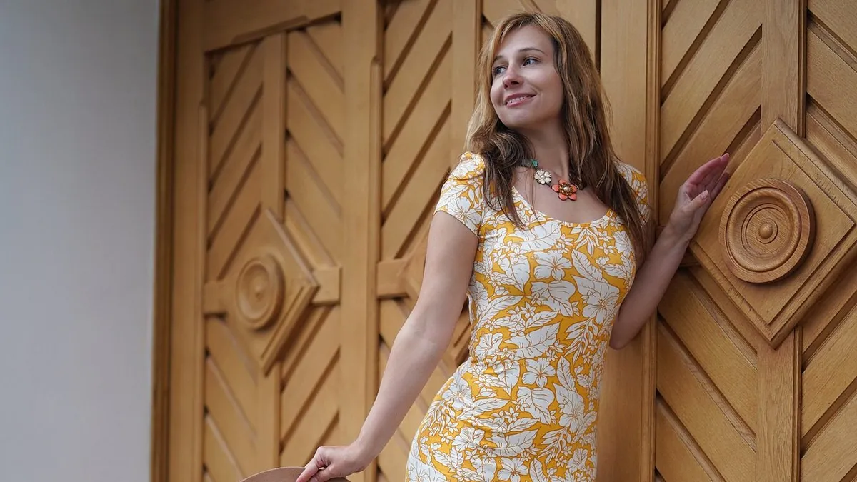 Modelo con un vestido amarillo entallado con estampado floral blanco