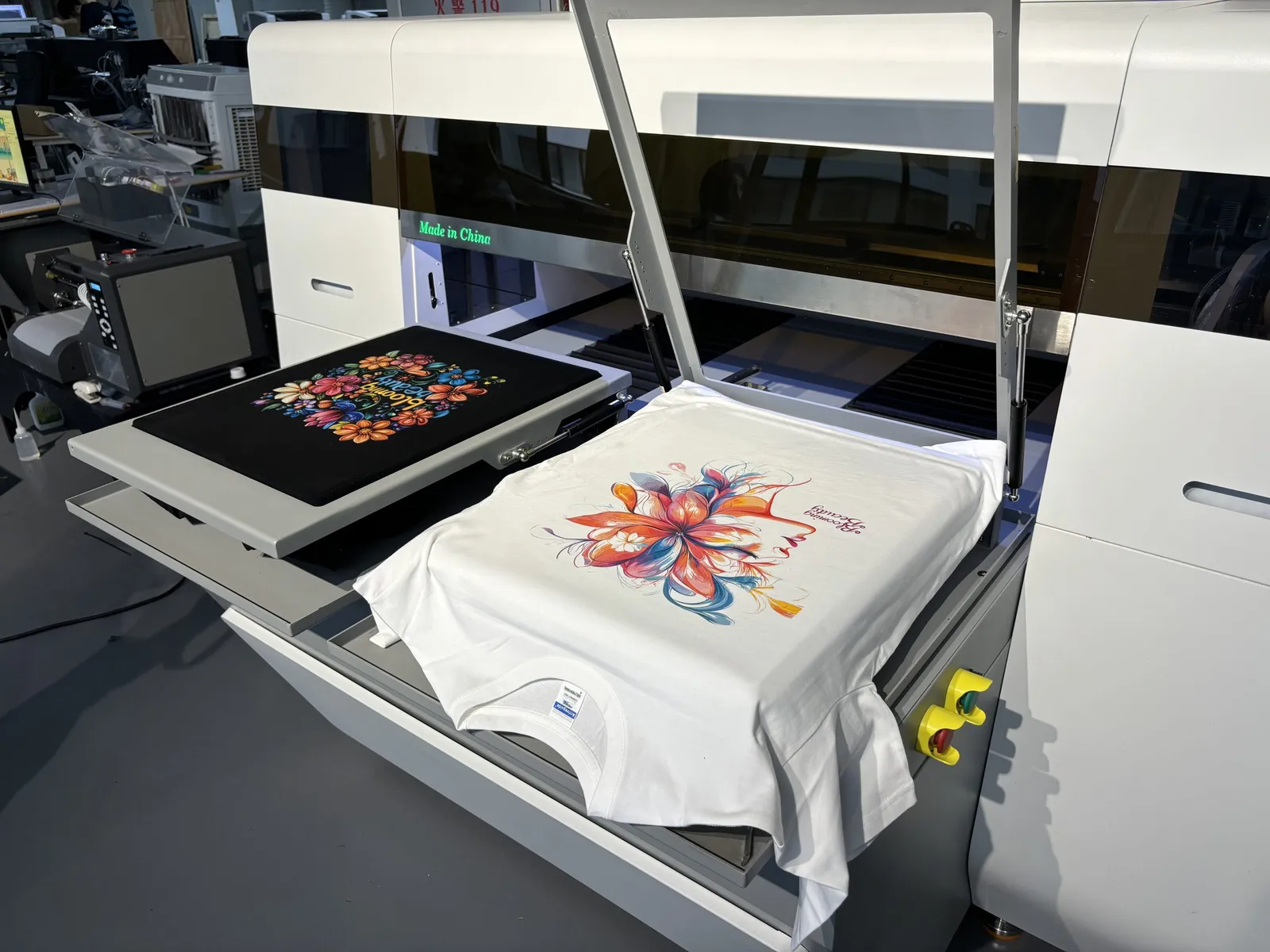 Dos camisetas estampadas cargadas en las platinas de una impresora industrial directa a prenda