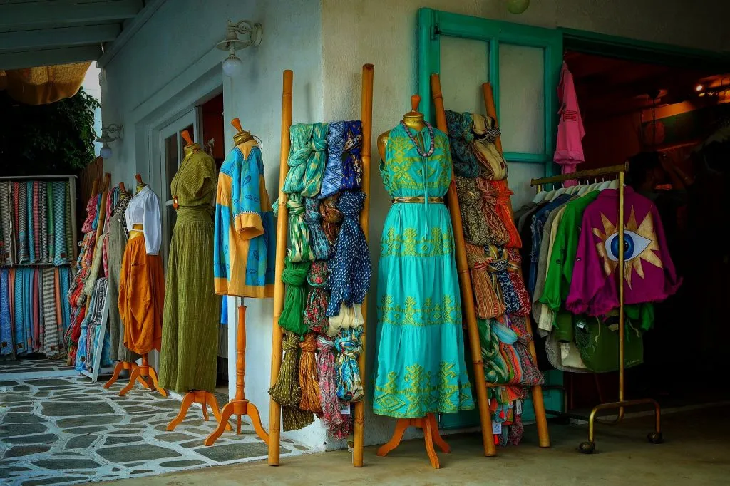 Vestidos estampados de colores, tejidos doblados y chaquetas expuestos a la entrada de una tienda de ropa