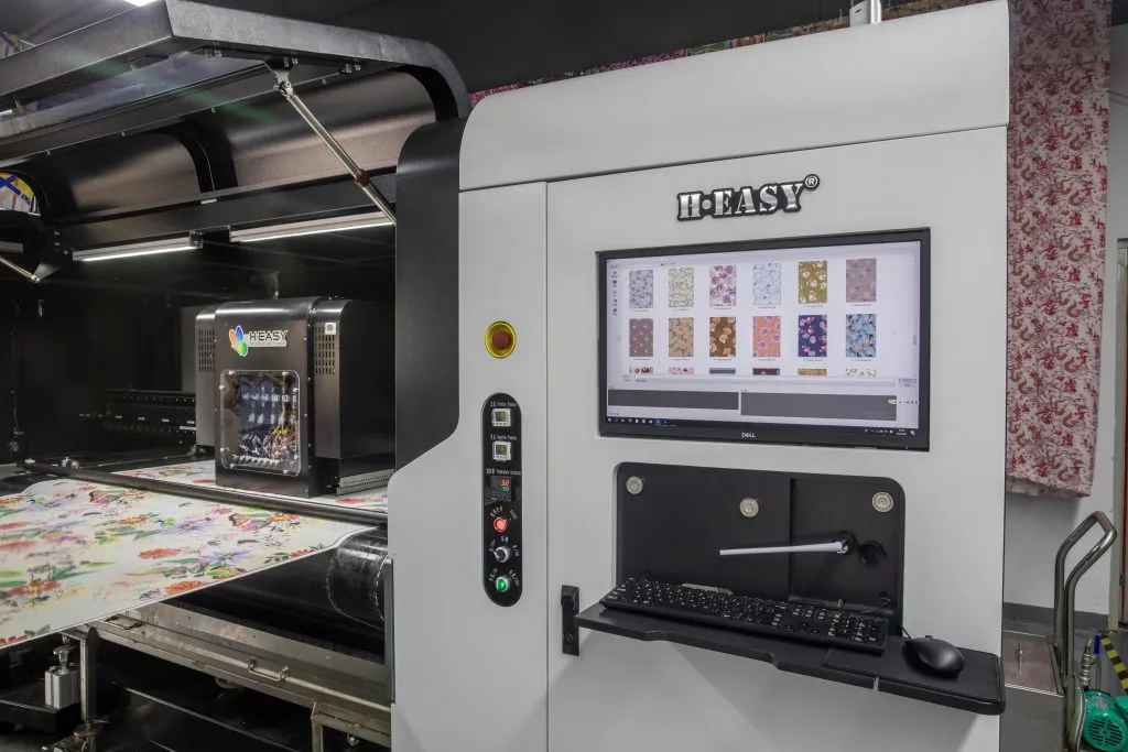 Textile printer control station and print carriage beside floral fabric on the platen