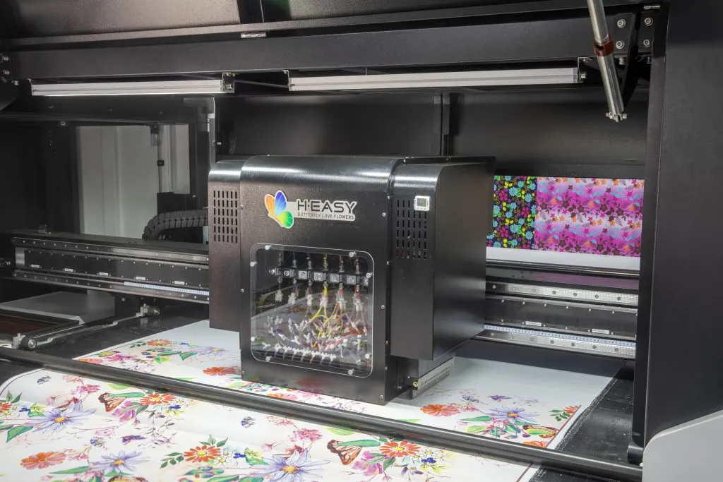 Print carriage moving over floral fabric inside a roll-to-roll textile printer
