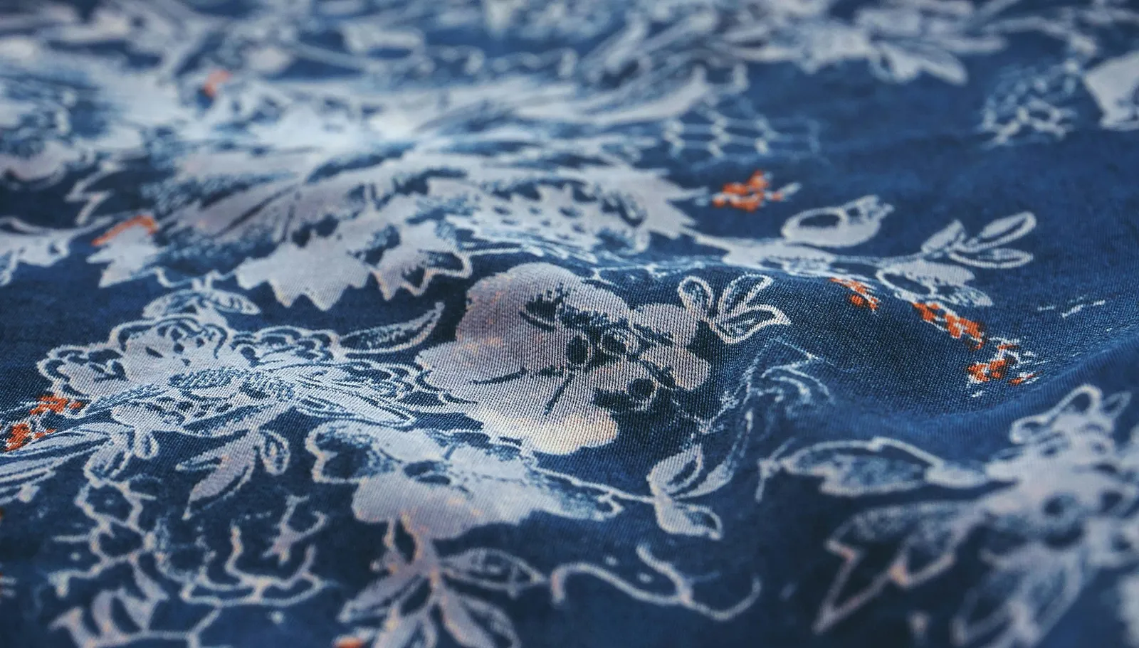 Primer plano de tejido estampado en azul con motivos florales y de línea superpuestos