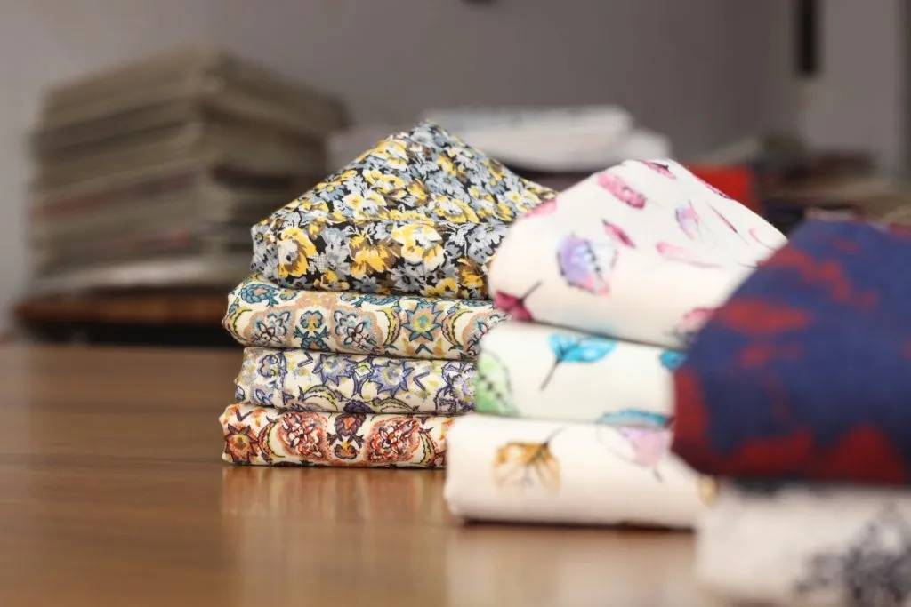 Pilas de tejidos estampados con motivos florales doblados sobre una mesa de trabajo